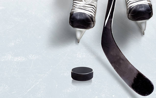 Ice Hockey Game With Copy Space Ice hockey game showing stick on puck with part of player's skates on ice and copy space. hockey skates stock pictures, royalty-free photos & images