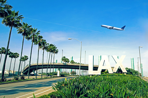 Los Angeles Airport sign with airplane flying overhead.