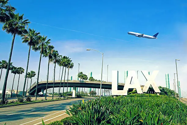 Los Angeles Airport sign with airplane flying overhead.