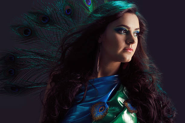 Woman in brilliant blue dress with peacock feathers design. Creative stock photo