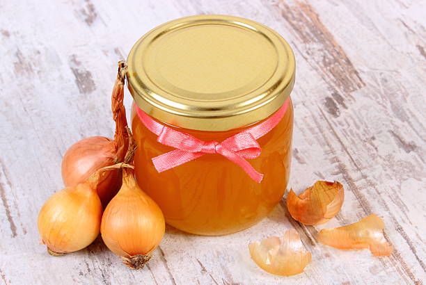 Fresh organic honey in glass jar and onions stock photo