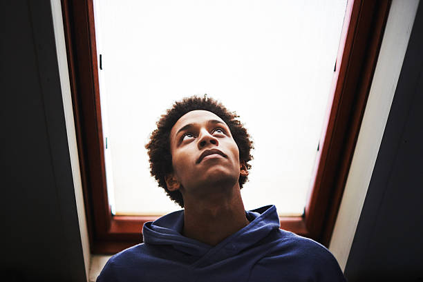 What is my higher purpose? Shot of a thoughtful young man looking out of a skylight of an attic at homehttp://195.154.178.81/DATA/i_collage/pu/shoots/806370.jpg low angle view stock pictures, royalty-free photos & images