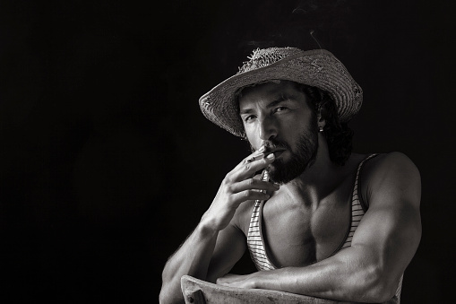 Attractive male smoking portrait on dark background, studio shot. Image taken with Canon 5D Mark II camera system and developed from camera RAW