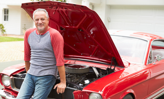 Retired Senior Man Working On Restored Classic Car Smiling To Camera