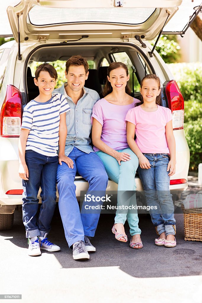 Smiling Family Sitting In Car Trunk On Street Full length portrait of smiling two generation family sitting in car trunk on street. Vertical shot. Car Stock Photo