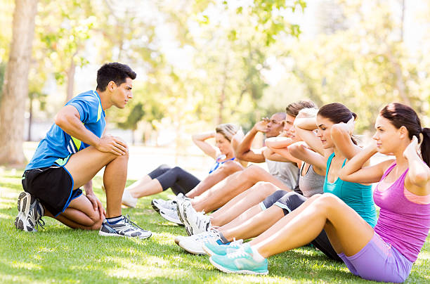 istock Fitness Instructor Motivating People In Doing Sit-Ups At Park 511671019