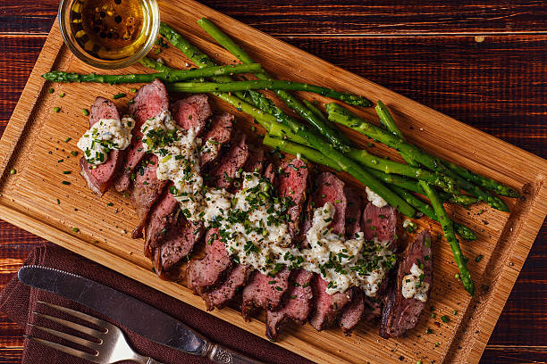 Steak with blue cheese sauce served with asparagus. Steak with blue cheese sauce served with asparagus on dark background. blue cheese stock pictures, royalty-free photos & images