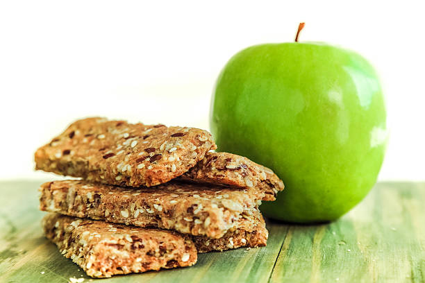 Healthy breakfast - Fresh shiny green apple and Granola Bar old green wooden table.Granny Smith Apple. White background.