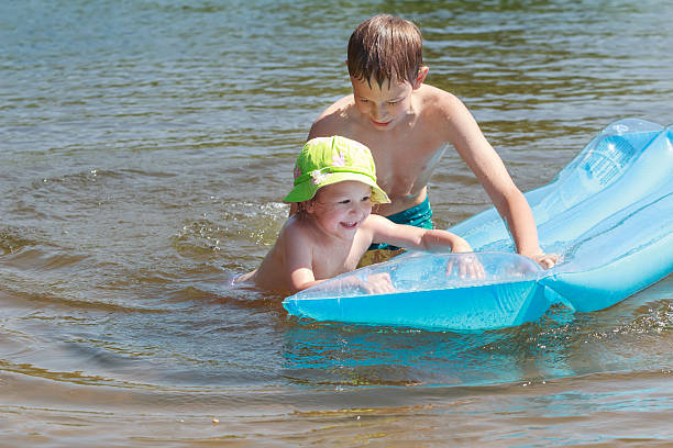 istock Sibling children having fun with inflatable blue pool lilo outdoor 511678988
