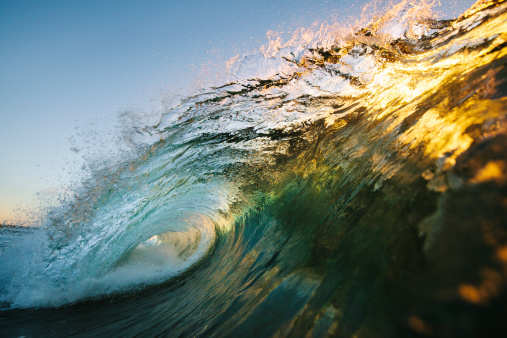 Sun reflecting through a golden lip of a wave early in the morning to produce an array of vibrant colours.