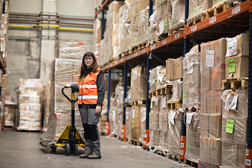 Portrait of a young woman moving boxes in a warehouse.
