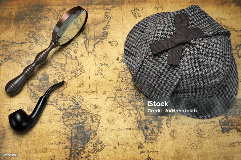 Deerstalker Hat, Magnifier And Smoking Pipe On Map Deerstalker Sherlock Holmes Hat, Vintage Magnifier And Smoking Pipe On The Old World Map Background. Overhead View.  Investigation Concept. Sherlock Holmes Stock Photo