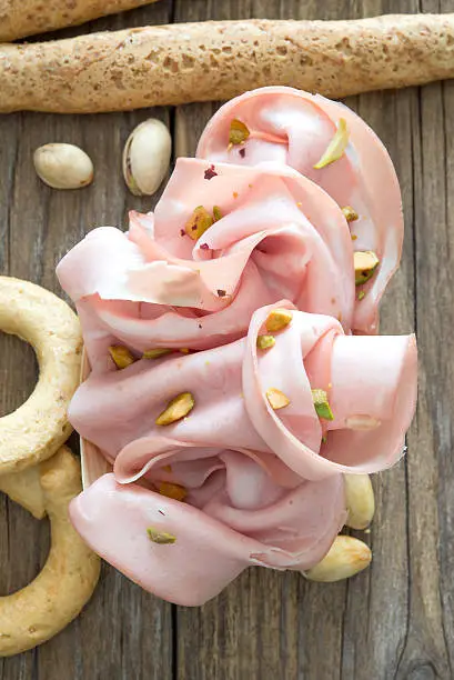 soft flowers mortadella and pistachios on wooden table