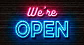 Neon sign on a brick wall - We are open