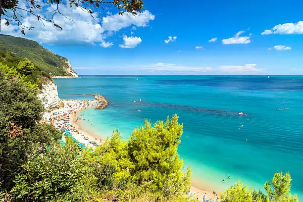 day view of famous beach crowded with tourists in Sirolo, Italy.