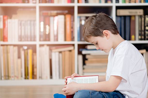 criança com um livro na biblioteca - picture book library preschool bookshelf - fotografias e filmes do acervo