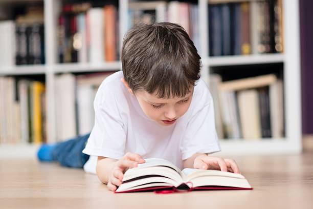 istock Boy lies on his stomach and reading a book 511727176