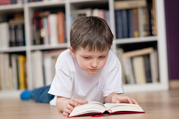 istock Little boy lies on his stomach and reading a book 511727224