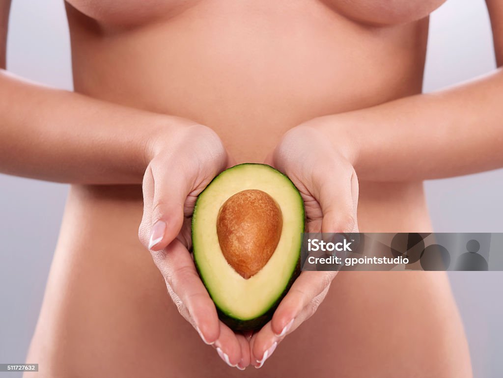 Naked woman holding the fresh avocado Avocado Stock Photo