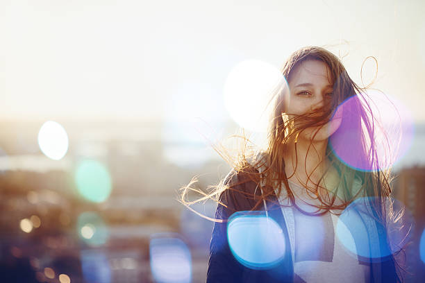 Young Woman Standing in Sunset Light Young Woman Standing in Sunset Light, Looking at Camera. Hair Fluttering in the Windi. Selective Focus, Bokeh Lights. free of charge photos stock pictures, royalty-free photos & images