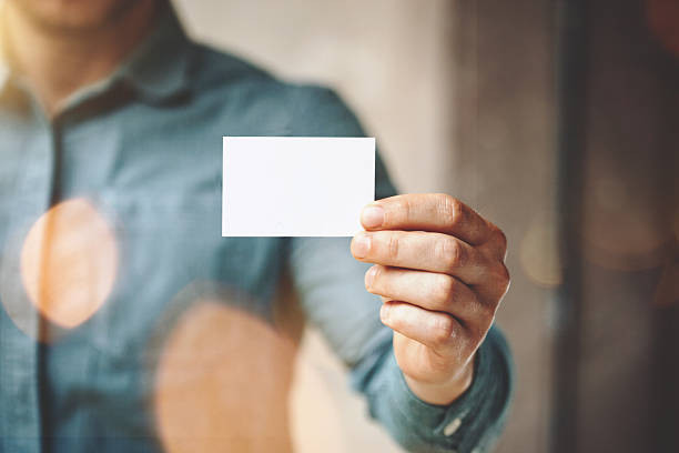 mann trägt blaue jeans hemd und zeigen leere weiße geschäft - template business business card holding stock-fotos und bilder