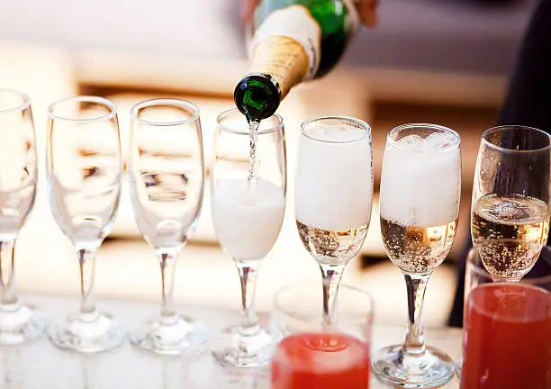 Waiter serving a glass of sparkling white wine