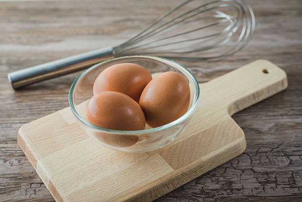 istock fresh eggs into glass bowl on wooden board 511739746