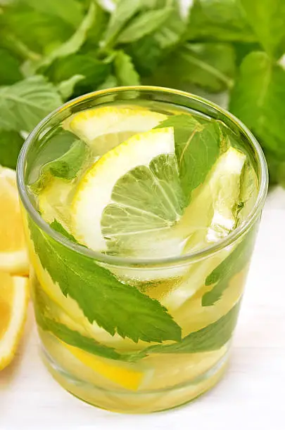 Lemonade with fresh lemon and mint in glass, close up view