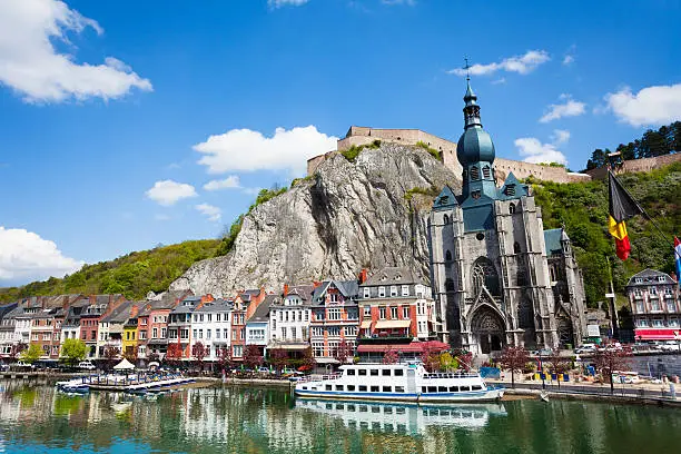 Beautiful Collegiate Church of Our Lady near Meuse river with white ship in Dinant, Belgium