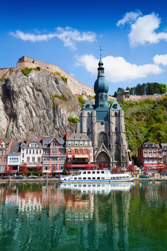 Dinant Collegiate Church of Our Lady near Meuse river with white ship in Belgium