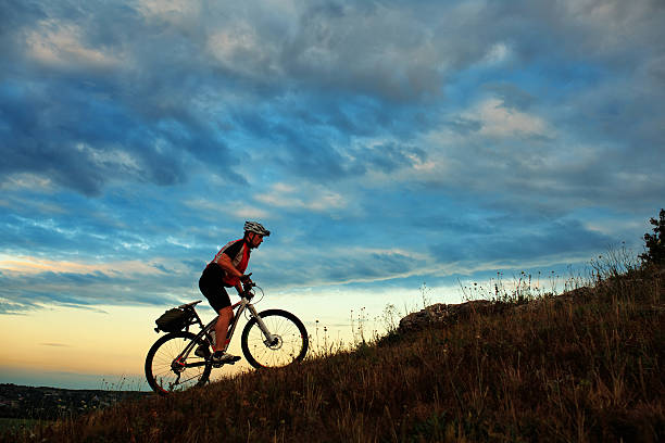 Silhouette of a biker and bicycle on sky background