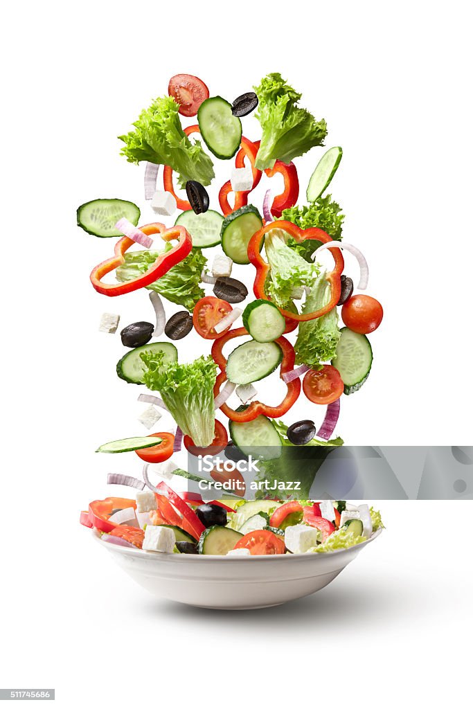 flying salad isolated on white background salad falling into the plate isolated on white background. Greek salad: red tomatoes, pepper, cheese, lettuce, cucumber and olives Healthy Eating Stock Photo