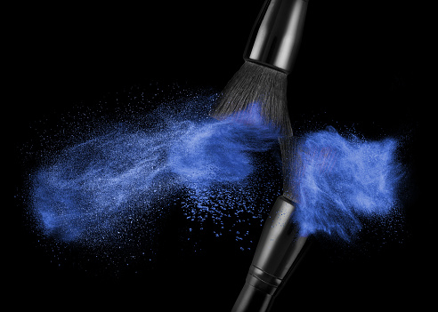 makeup brush with blue powder isolated on black