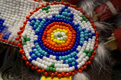 A macro photo of Native American Indian bead work from a costume.  It is very colorful and has a star shape and circular pattern.  
