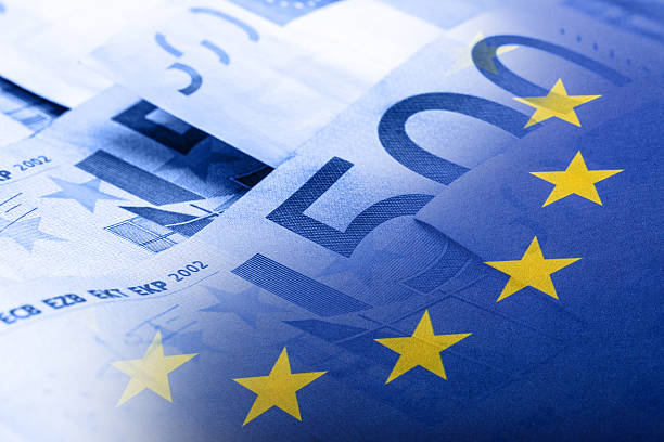 acenando um bandeira colorida união europeia em um fundo de dinheiro de euro - european union coin european union currency euro symbol coin - fotografias e filmes do acervo