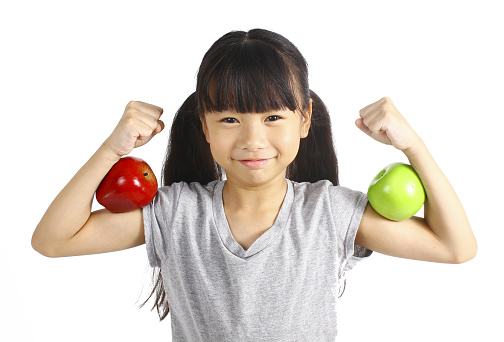 A little girl flexes her muscle while showing off the apple that made her strong and healthy 