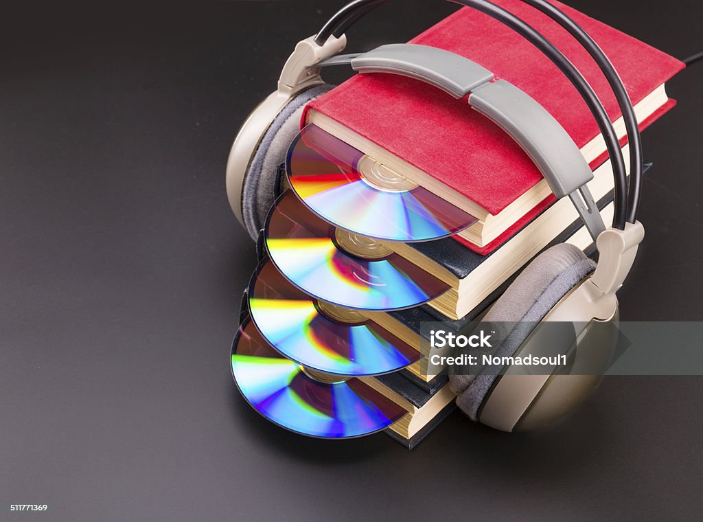 Cd sticks out from red books with headphones on it Cd disk sticks out from pile of red books with headphones on books Book Stock Photo