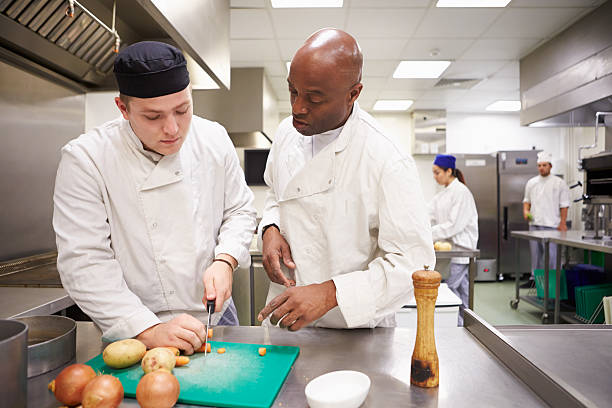 учитель, помогая студентам обучение для работы в обслуживание - chef trainee cooking teenager стоковые фото и изображения