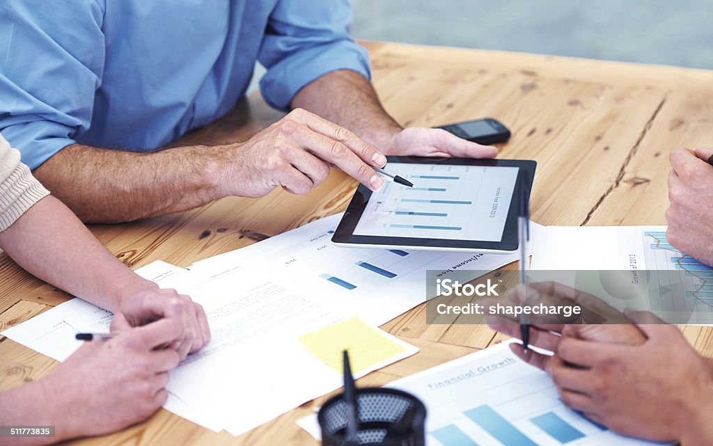 Working through the figures Cropped shot of businesspeople in a meeting and using a digital tablet Business Meeting Stock Photo