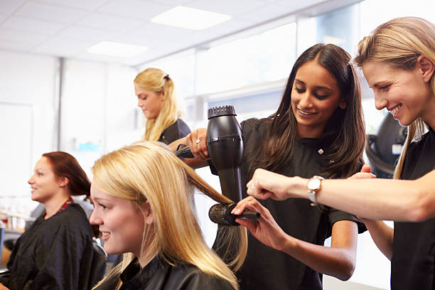 teacher helping students training to become hairdressers - saç kesmek stok fotoğraflar ve resimler