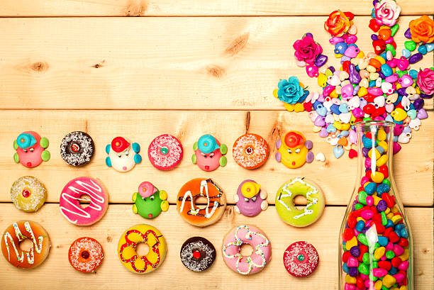 Sweet donuts pastel color with rose flower on wooden background