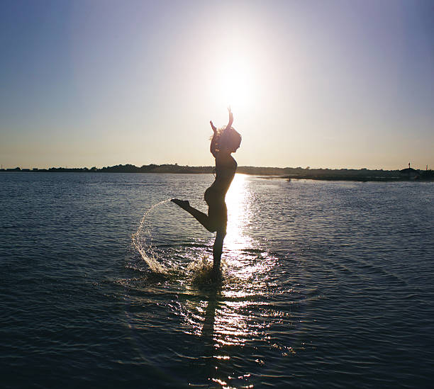 istock Happy woman jumping in the sunset sea 511787774