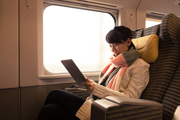 Young woman using her tablet computer while traveling by train stock photo
