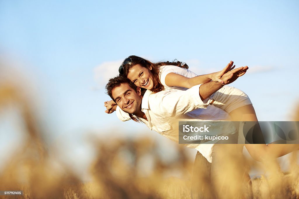 I'm Tinkerbell if you'll be Peter Pan A playful young couple stretching out their arms while standing outside Adult Stock Photo