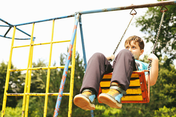 istock Cute Blond Boy Swinging at the Playground 511793622