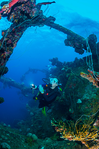 A female diver exploring the wreck Teshio Maru a Japanese Army Cargo Ship with 321 feet (98) on it's length, and was built in 1942-1944. The Teshio is one of the fishiest wrecks in Palau. 
