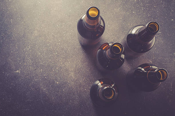 botellas de cerveza en la oscuridad, tabla - empty brewery fotografías e imágenes de stock