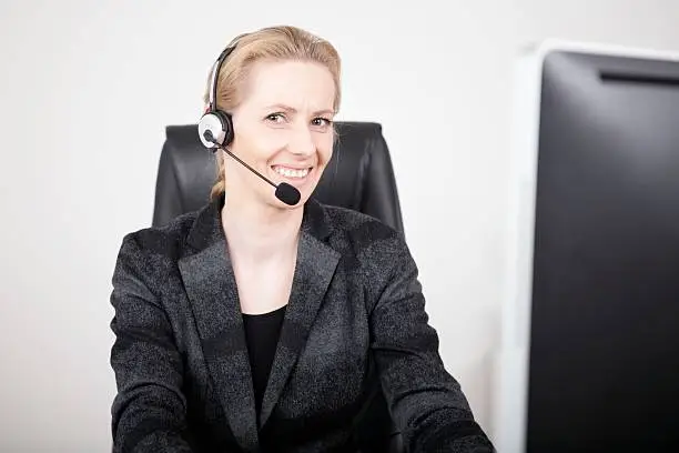 Photo of Smiling Manageress Wearing Headset at her Office
