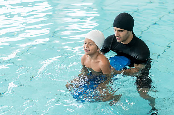 Boy taking swimming lessons Young boy taking swimming lessons and learning how to float with help of his instructor hydrotherapy stock pictures, royalty-free photos & images