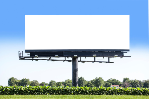 Blank billboard standing in a soybean field along a road.